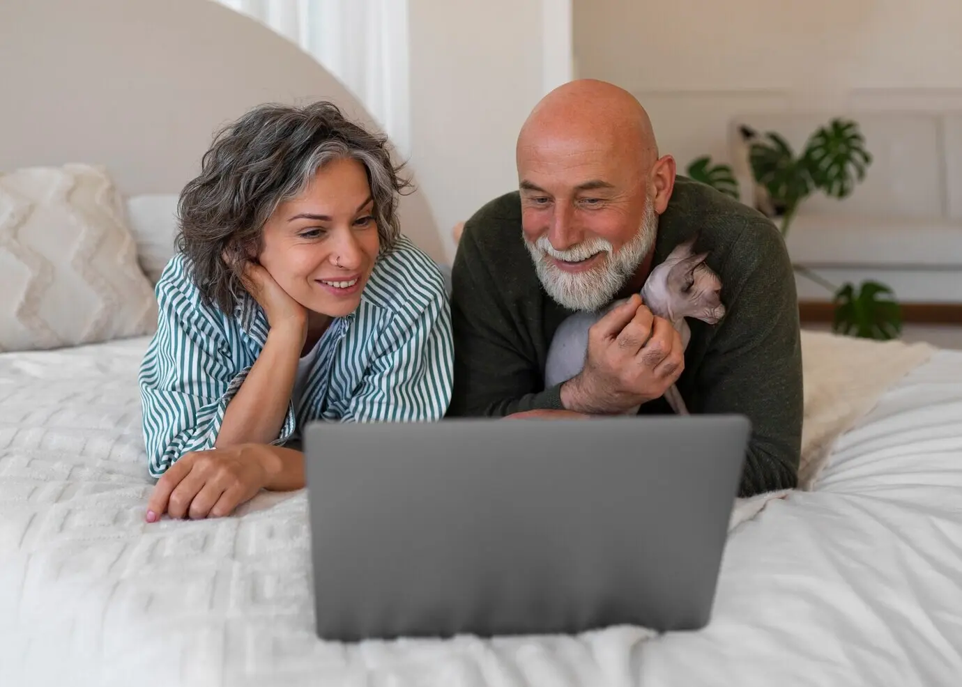 Ganzkörperaufnahme eines Seniorenpaares mit Katze zu Hause.
